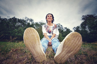 Portrait of smiling young woman sitting on plants against sky
