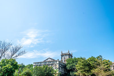 Low angle view of trees and building against sky