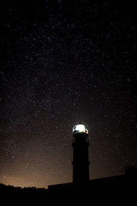 Low angle view of silhouette lighthouse against sky at night