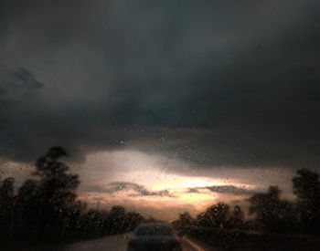 Low angle view of silhouette trees against sky during rainy season