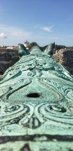 Close-up of carving on old wall against sky