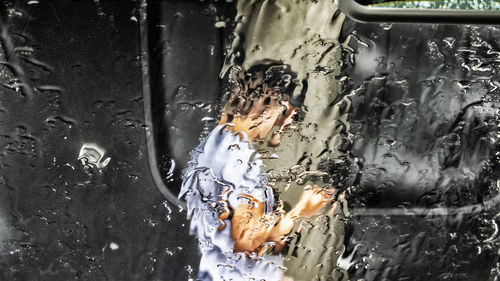 Close-up of person seen through wet glass