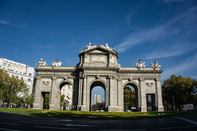 Low angle view of alcala gate against sky in city
