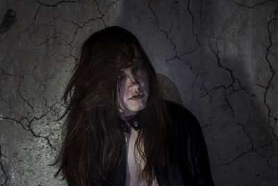 Portrait of young woman standing against wall