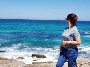 Young woman looking at sea against sky