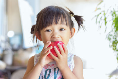 Close-up portrait of girl eating apple at home