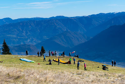 People on field by mountains against sky