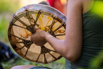 Midsection of man holding tribal drum outdoors