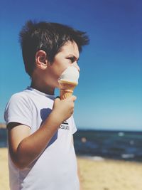 Full length of man holding ice cream at beach against sky