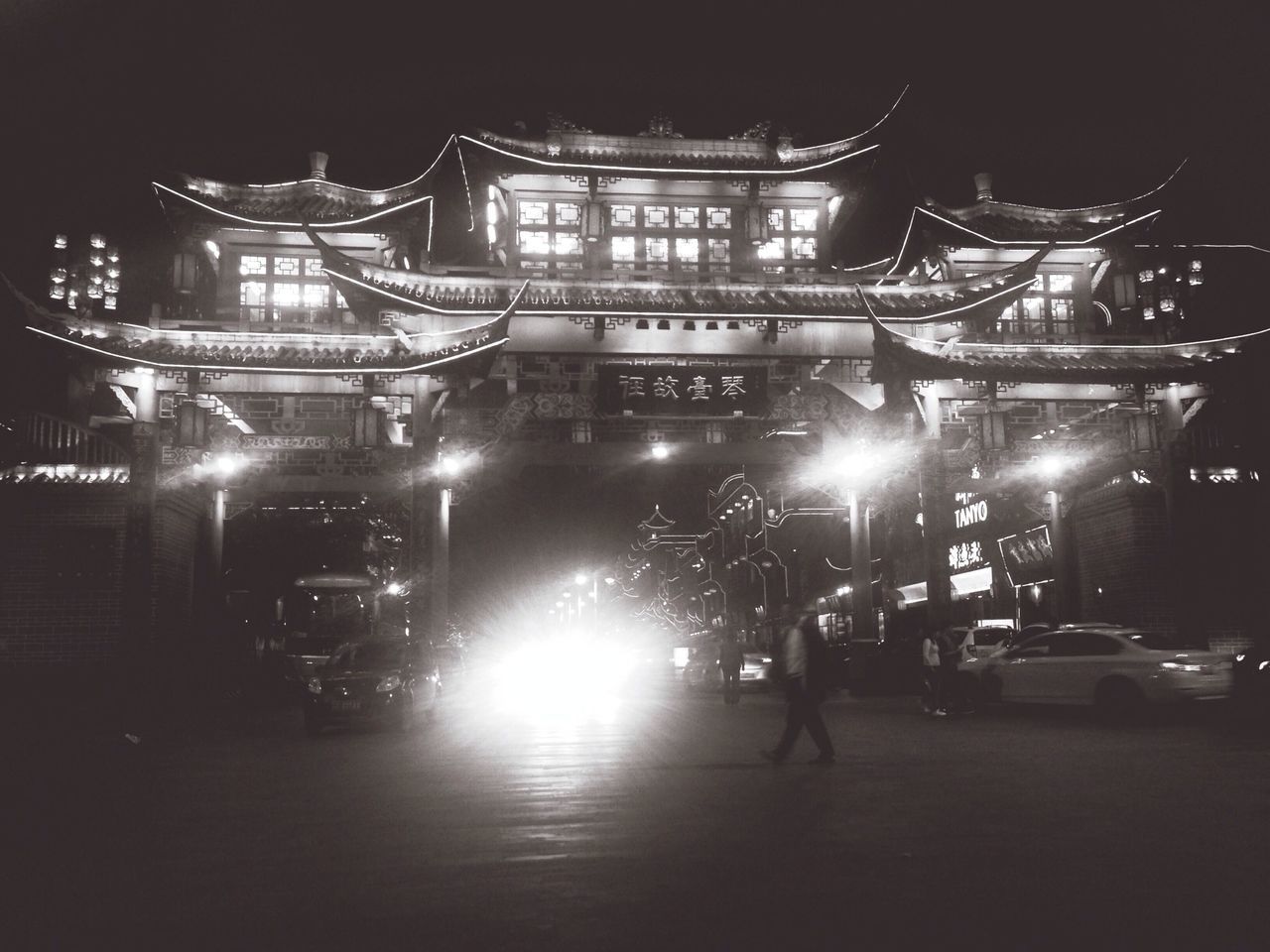 illuminated, night, building exterior, architecture, built structure, land vehicle, car, transportation, street, city, mode of transport, street light, lighting equipment, city street, road, city life, sky, light - natural phenomenon, dark, building