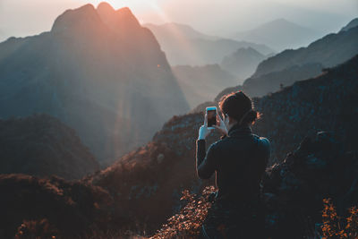 Rear view of woman photographing mountains