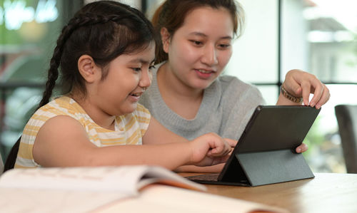 Portrait of smiling young woman using laptop at home