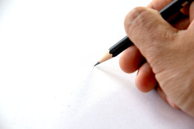 Close-up of hand holding pen against white background