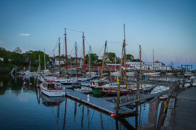 Boats moored at harbor against clear sky