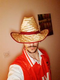 Portrait of man wearing hat against wall