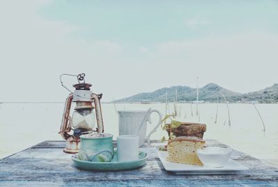 View of drink on table by sea against sky