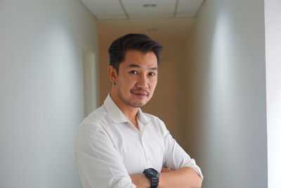 Portrait of young man standing against wall