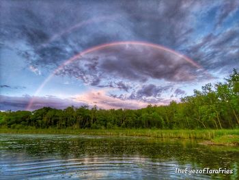 Scenic view of rainbow over lake against sky