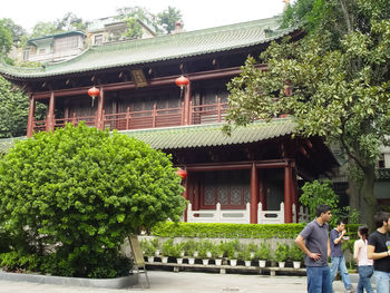 People outside house against trees and building