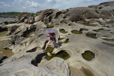 Side view of a woman walking on rocky beach