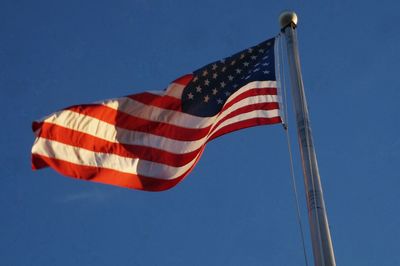 Low angle view of flag against blue sky