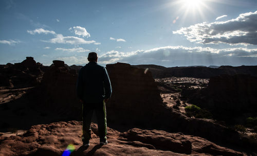 Rear view of man standing on rock against sky