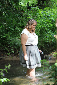 Side view of woman standing in river against plants