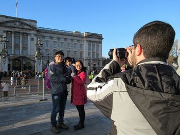 Rear view of people photographing against clear sky