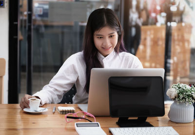 Portrait of young woman using smart phone on table