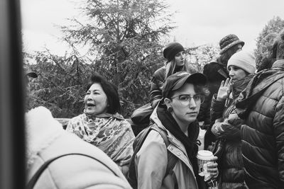 Portrait of friends looking at camera against trees