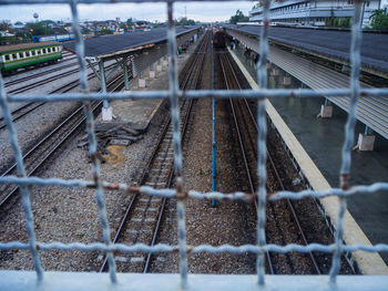 View of railroad tracks seen through metal fence