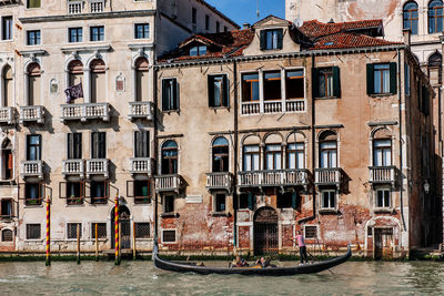 Gondola on canal by buildings in city