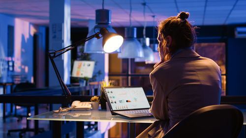 Rear view of woman using laptop at table