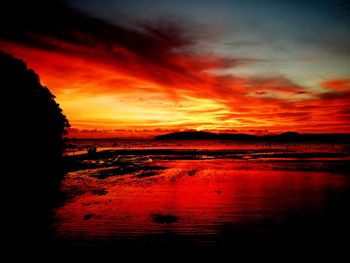 Scenic view of lake against dramatic sky during sunset