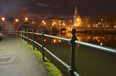 Illuminated bridge over river in city at night