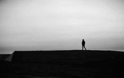 Silhouette man standing on rock against sky