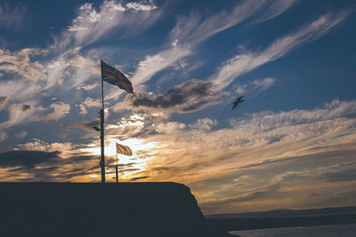 Low angle view of silhouette flag against sky during sunset