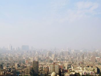 Aerial view of buildings in city against sky