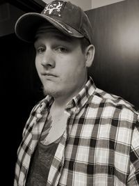 Portrait of young man wearing hat against black background