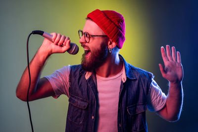 Man screaming on mic against green background