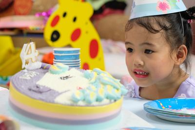 Girl looking at birthday cake on table during celebration