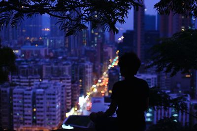 Silhouette woman overlooking illuminated city from terrace at night