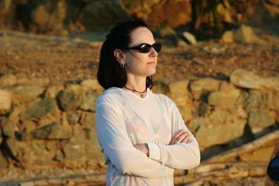 Side view of young woman wearing sunglasses standing outdoors