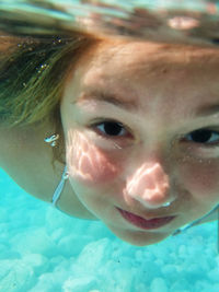 Close-up portrait of smiling girl swimming in pool
