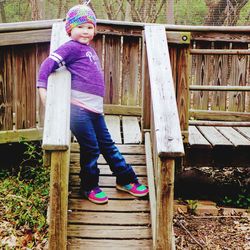 Full length of cute girl standing by fence