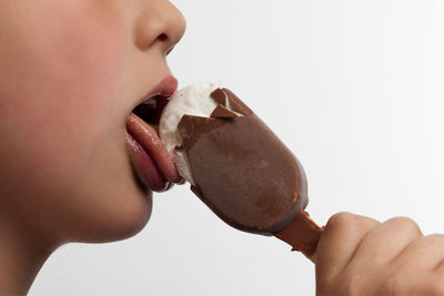 Close-up of woman eating ice cream against white background