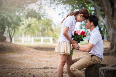 Young couple kissing on flower against trees