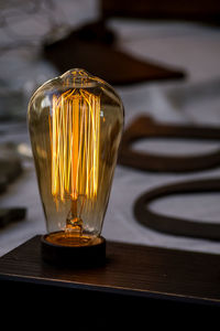 Close-up of illuminated light bulb on table