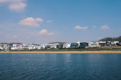 Houses by sea against sky in city