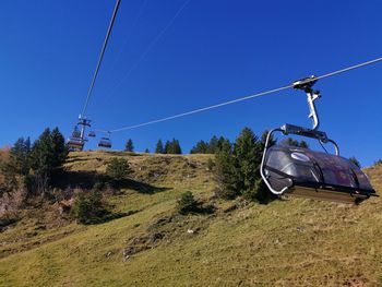 Overhead cable car on field against clear blue sky